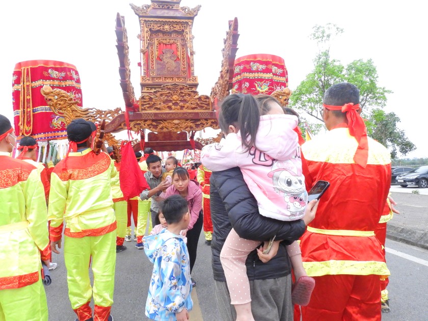 Tục lệ cho trẻ em chui qua kiệu rước với ước muốn mạnh khỏe, học hành giỏi giang và đỗ đạt. Ảnh: Báo PLVN